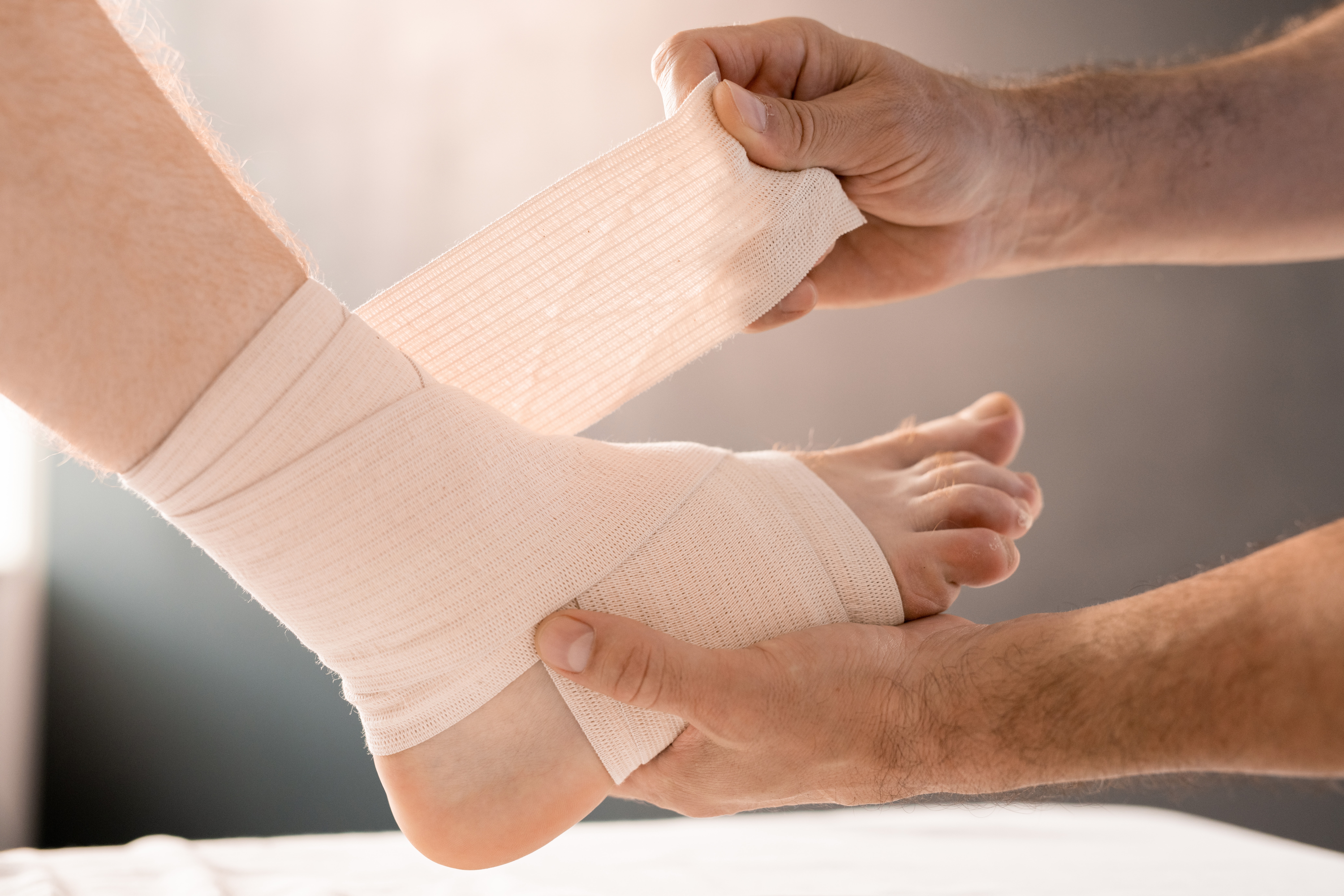 GauzeAroundFootAndAnkle Hands of clinician wrapping foot and leg of patient with flexible bandage
